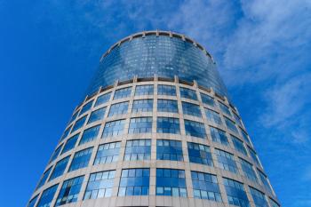 Modern glass office building on blue sky background
