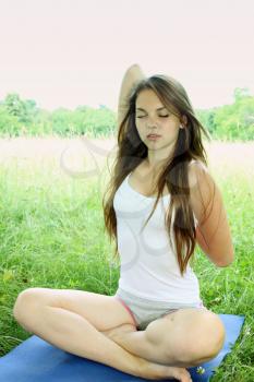Young beautiful woman practices yoga in nature