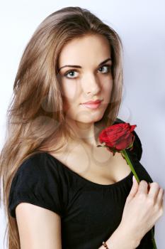 Beautiful young woman holds a red rose