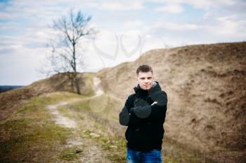 Young Handsome Man Stayed In Field, Meadow In Autumn Day. Casual Style - Jeans, Jacket