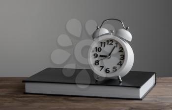 Alarm clock standing on of closed book