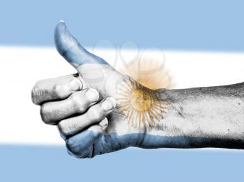 Old woman with arthritis giving the thumbs up sign, wrapped in flag pattern, Argentina