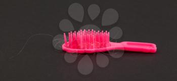 Pink toy brush with hair isolated on black