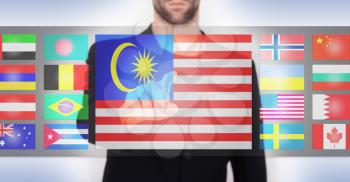 Hand pushing on a touch screen interface, choosing language or country, Malaysia