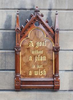 Decorative wooden sign hanging on a concrete wall - A goal without a plan is jist a wish