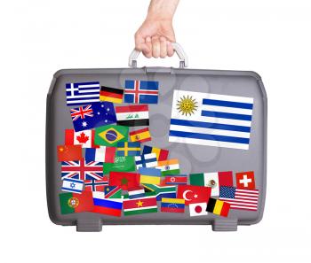 Used plastic suitcase with lots of small stickers, large sticker of Uruguay