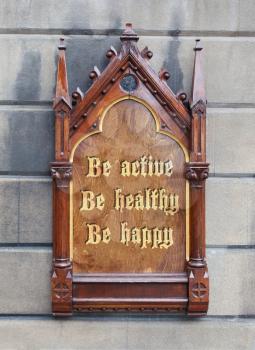 Decorative wooden sign hanging on a concrete wall - Be active, be healthy, be happy