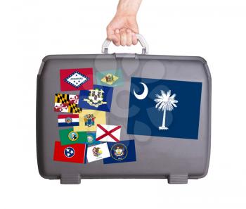 Used plastic suitcase with stains and scratches, stickers of US States, South Carolina