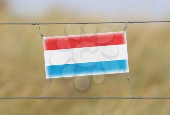 Border fence - Old plastic sign with a flag - Luxembourg