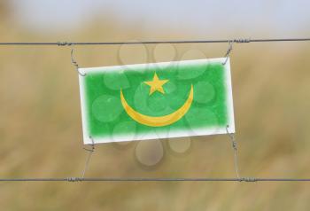 Border fence - Old plastic sign with a flag - Mauritania