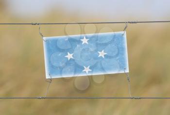 Border fence - Old plastic sign with a flag - Micronesia