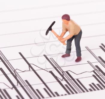 Miniature worker with pickaxe working on a graph