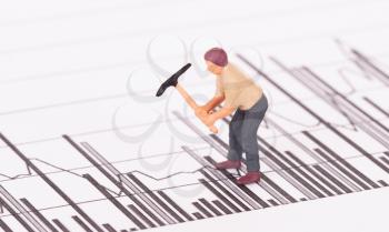 Miniature worker with pickaxe working on a graph