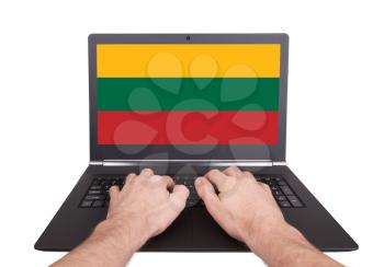 Hands working on laptop showing on the screen the flag of Lithuania