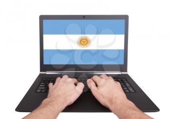 Hands working on laptop showing on the screen the flag of Argentina