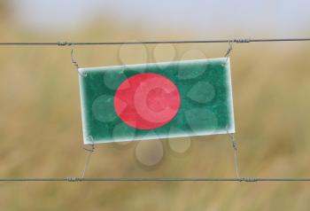 Border fence - Old plastic sign with a flag - Bangladesh