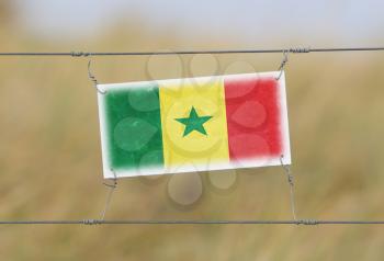 Border fence - Old plastic sign with a flag - Senegal