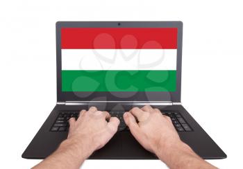 Hands working on laptop showing on the screen the flag of Hungary