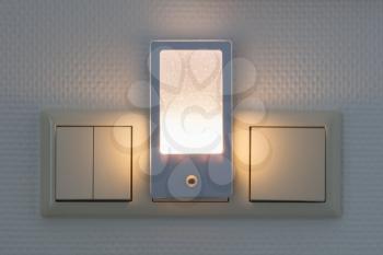 Plastic nightlight illuminating the wall and light switch