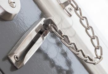 Door chain on a grey door, security measures