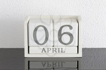 White block calendar present date 6 and month April on white wall background