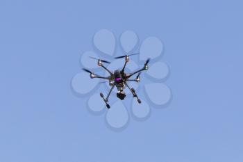 Flying drone with blue sky background controlled by professional photographer