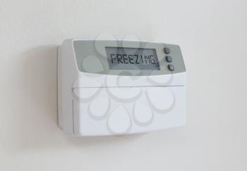 Vintage digital thermostat hanging on a white wall - Covert in dust - Freezing