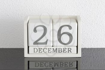White block calendar present date 26 and month December on white wall background