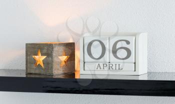 White block calendar present date 6 and month April on white wall background