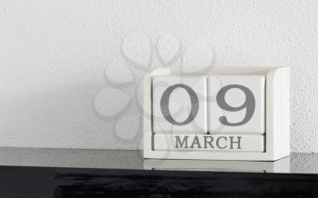 White block calendar present date 9 and month March on white wall background