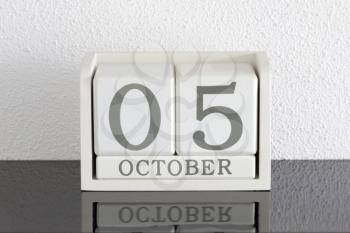 White block calendar present date 5 and month October on white wall background