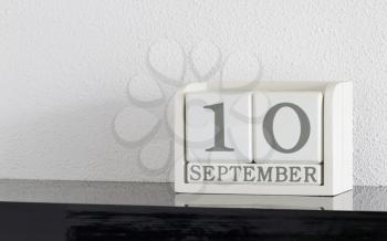 White block calendar present date 10 and month September on white wall background