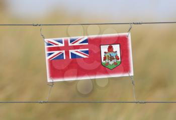 Border fence - Old plastic sign with a flag - Bermuda