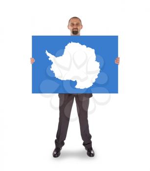 Smiling businessman holding a big card, flag of Antarctica, isolated on white