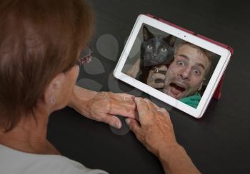 Senior woman with tablet contacting her family