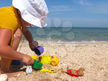 little girl plays on the sand at the sea