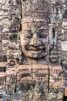 Stone faces of Bayon temple is Khmer ancient temple in complex Angkor Wat in Siem Reap, Cambodia in a summer day