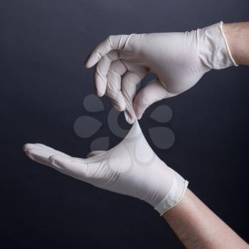 Male hands in latex gloves on dark background