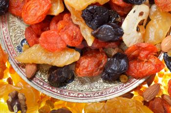 top view of oriental dessert - dried sweet fruits and nuts on plate close up