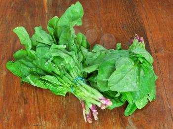 two bunches of fresh green spinach on wooden table