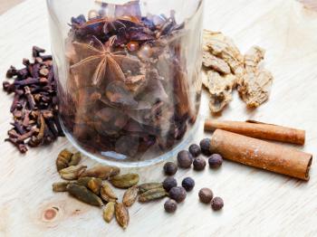 glass bottle and spices for mulled wine on wooden table close up