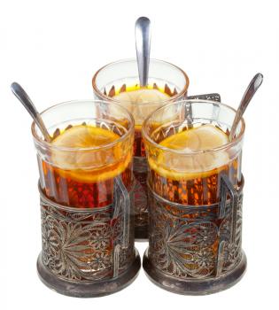 retro glasses in old silver glass holders with black tea and lemon isolated on white background