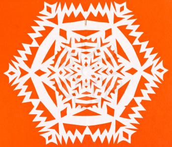 hand made cut out white snowflake on orange paper