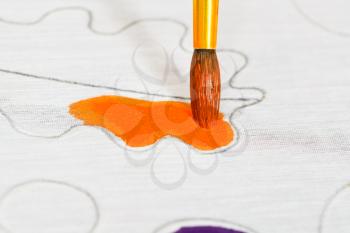 painting orange ornament on silk canvas with brush close up