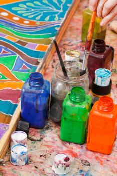 paintbrushes and bottles with color pigments for cold batik