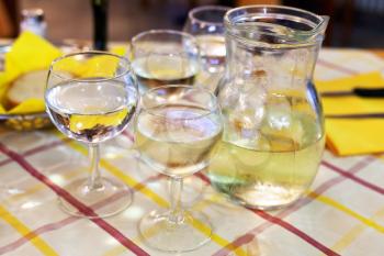glass jug with local white wine and glasses on table in italian restaurant