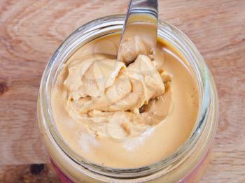 peanut butter with knife in a glass jar on wooden table