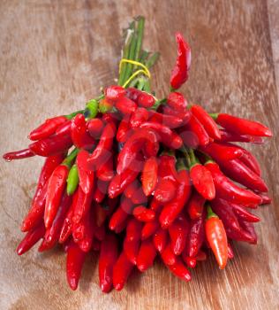 bunch of fresh small cayenne red pepper on wood table