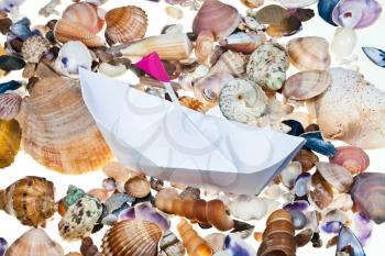 white paper boat with flag on background from sea shells