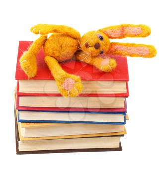 felt soft toy rabbit lies on stack of books isolated on white background